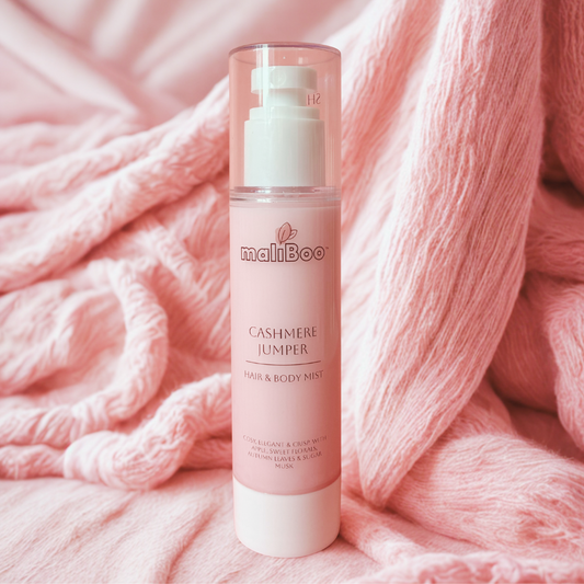Maliboo Cashmere Jumper Hair and Body Mist bottle on soft knit fabric with cozy neutral tones. Vegan, cruelty-free fragrance with warm cashmere and vanilla notes.