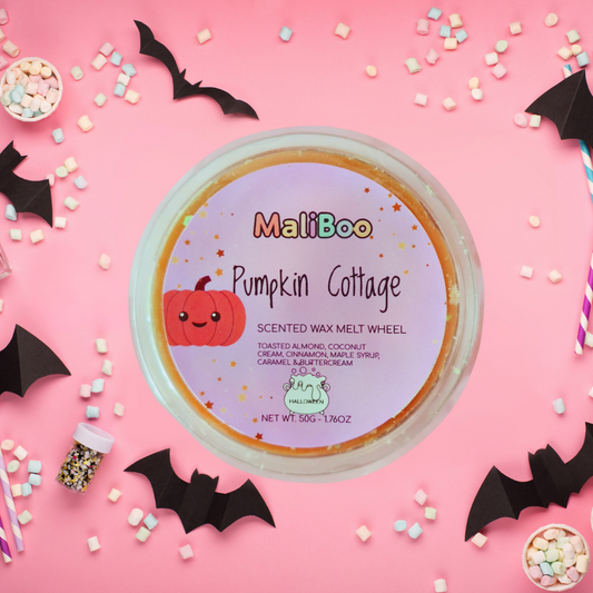 MaliBoo Pumpkin Cottage scented wax melt wheel on a pink background with Halloween decorations.