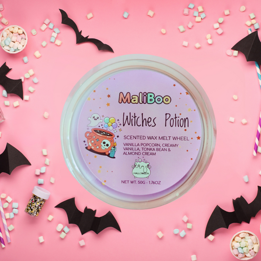 MaliBoo Witches Potion scented wax melt wheel on a pink background with Halloween decorations.