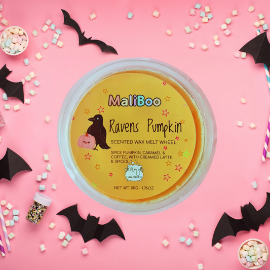 MaliBoo Ravens Pumpkin scented wax melt wheel on a pink background with Halloween decorations.