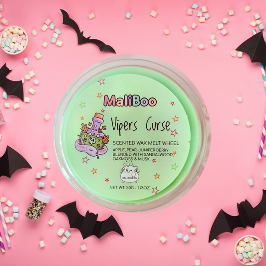 MaliBoo Vipers Curse scented wax melt wheel on a pink background with Halloween decorations.